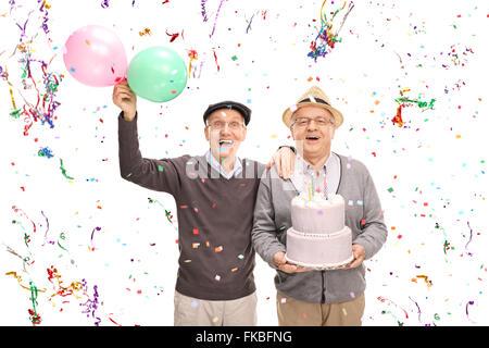 Deux hauts messieurs célébration anniversaire avec un gâteau et des ballons isolé sur fond blanc Banque D'Images