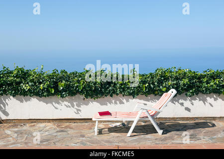 Livre sur la chaise à côté de piscine de lierre sur le mur et le ciel bleu Banque D'Images