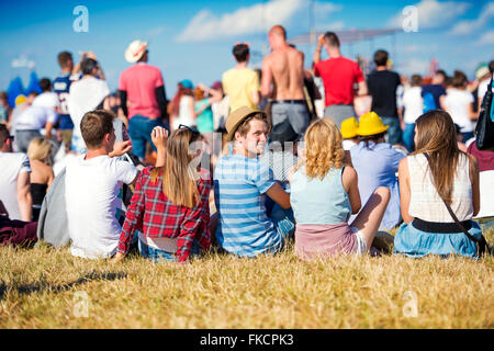 Les adolescents au festival de musique d'été, assis sur l'herbe Banque D'Images