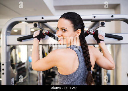 Femme dans la salle de sport de la torsion du dos sur la machine de câble Banque D'Images