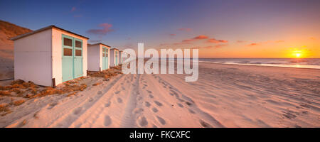 Une rangée de cabines de plage sur une plage de l'île de Texel aux Pays-Bas. Photographié au coucher du soleil. Banque D'Images