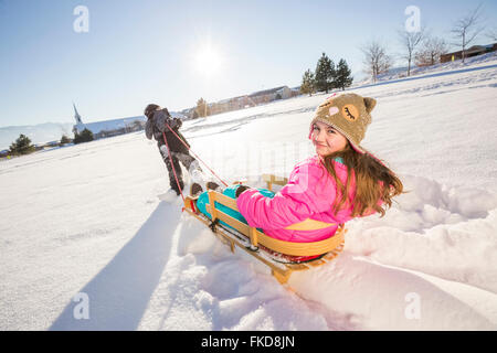 Enfants (8-9, 10-11) jouant avec la neige en traîneau Banque D'Images