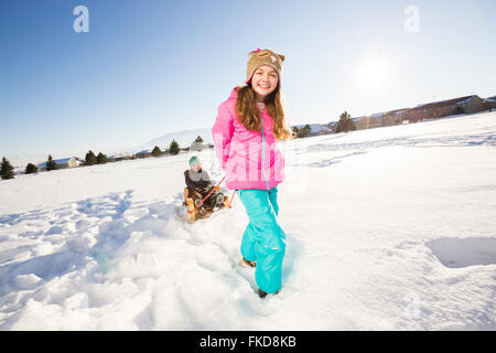 Enfants (8-9, 10-11) jouant avec la neige en traîneau Banque D'Images