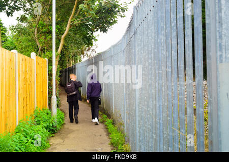 Deux garçons marcher entre deux murs. Londres, Angleterre, Royaume-Uni. Banque D'Images