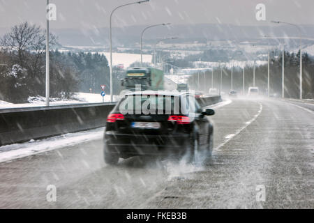 Les voitures qui circulent sur la route glissante lors de verglas causant des conditions hivernales dangereuses route humide en hiver / printemps Banque D'Images