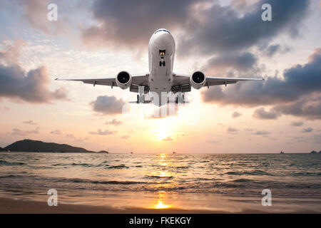 L'atterrissage de l'avion dans le coucher du soleil Banque D'Images