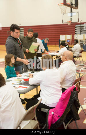 Detroit, Michigan, USA. 8 mars, 2016. Un homme attend pour obtenir son bulletin pour l'élection présidentielle primaires du Michigan comme sa fille montres. Crédit : Jim West/Alamy Live News Banque D'Images