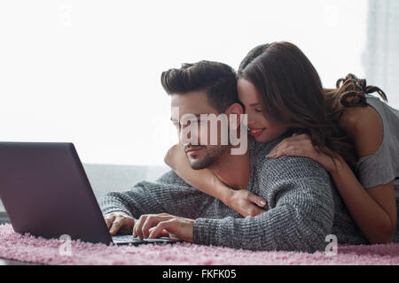 Jeune couple avec tablet allongé sur un tapis, la technologie wi-fi Banque D'Images