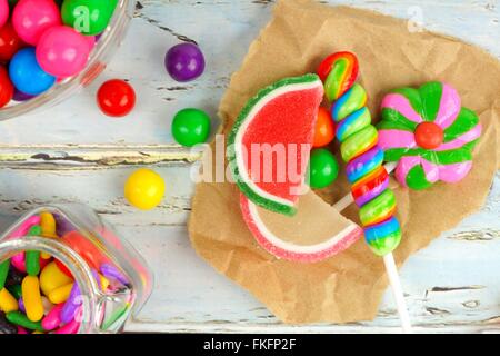 Assortiment de bonbons sucrés dans une grappe sur papier avec fond en bois rustique Banque D'Images