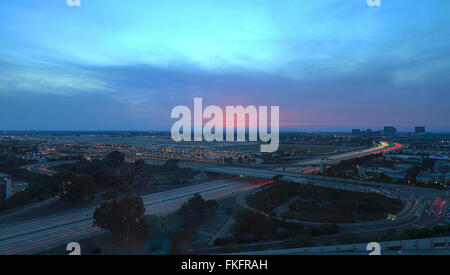 Vue aérienne de l'aéroport John Wayne dans Orange County, en Californie, au coucher du soleil avec la pluie dans l'air Sentiers de lumière à travers le 405 highw Banque D'Images