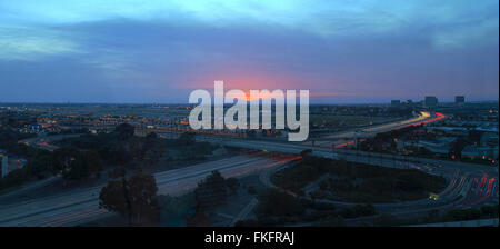 Vue aérienne de l'aéroport John Wayne dans Orange County, en Californie, au coucher du soleil avec la pluie dans l'air Sentiers de lumière à travers le 405 highw Banque D'Images