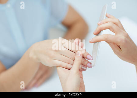 Close-up of a woman in a nail salon receiving manicure par une esthéticienne au salon de manucure Banque D'Images