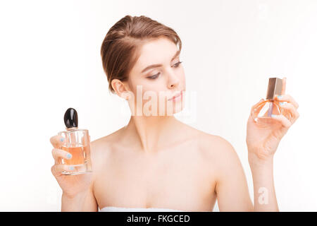 Portrait of attractive young woman holding deux bouteilles de parfums sur fond blanc Banque D'Images
