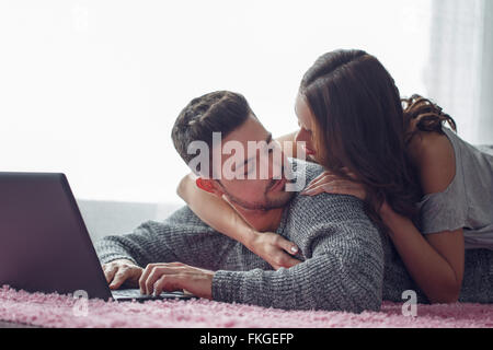 Jeune couple avec coffre allongé sur un tapis, à l'autre, la technologie wi-fi Banque D'Images