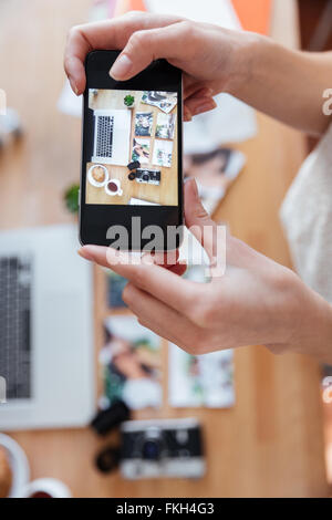 Libre de mains de jeune femme prendre des photos d'objets sur son lieu de travail using smartphone Banque D'Images