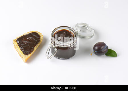 Pot de confiture de prunes, de prune et de tranche de baguette sur fond blanc Banque D'Images