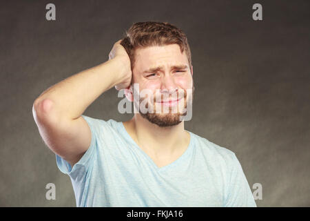 Portrait de triste déprimé bel homme chemise en pleurant. Jeune homme posing in studio sur noir. Banque D'Images