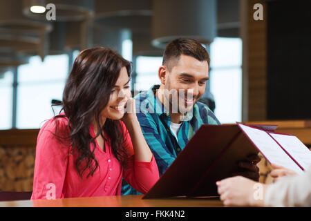 Smiling couple avec des menus au restaurant Banque D'Images