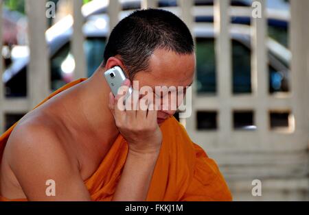 Chiang Mai, Thaïlande - 21 décembre 2012 : Une robe orange Un moine assis dans une place de la ville en utilisant son téléphone cellulaire Banque D'Images