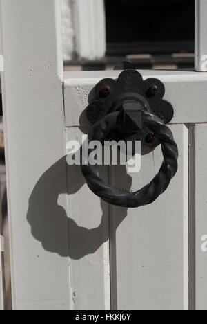 Un rond noir heurtoir, sur une porte blanche, d'une maison d'habitation. Banque D'Images