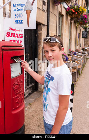 Un garçon de 11 ans affiche une carte postale de ses vacances en famille au Royaume-Uni Banque D'Images