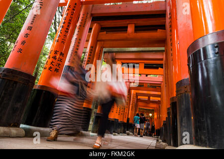 Les touristes de passer sous le torii, Fushimi Inari Taisha, Fushimi-ku, Kyoto, Japon. Banque D'Images