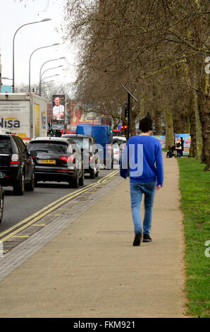 Un homme marche le long de la chaussée le long de Uxbridge Road sur le bord de Shepherds Bush Common Banque D'Images