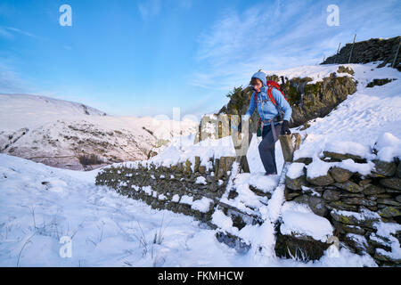 Traversée d'un randonneur stile sur un mur de pierre à Hartsop au-dessus comment dans le Lake District. Banque D'Images