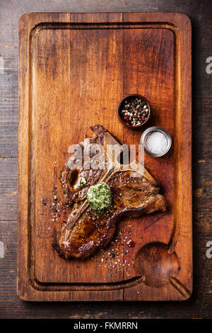 T-bone steak grillé au beurre d'herbes et de sel et poivre sur planche à découper en bois Banque D'Images