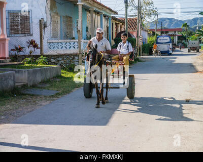 Chariot avec père et fils équitation le long d'une rue à Viñales, Cuba. Banque D'Images