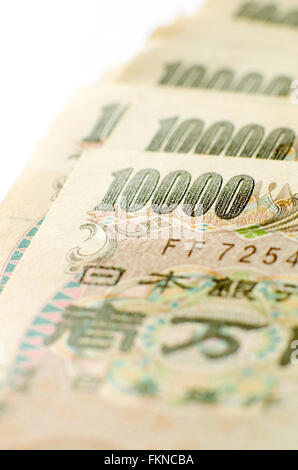 Gros plan d'une pile de 10000 yen notes sur fond blanc. Banque D'Images