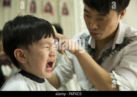 Huludao, province de Liaoning en Chine. 10 Mar, 2016. Un enfant pleure comme une coiffure lui donne une coupe de cheveux à un coiffeur à l'Longtaitou Festival à Huludao, nord-est de la Chine, la province de Liaoning, 10 mars 2016. Le Longtaitou Eryueer ou Festival, Festival, ce qui signifie 'dragon soulève tête" en chinois, est un festival traditionnel chinois tenue le deuxième jour du deuxième mois dans le calendrier lunaire chinois. Les Chinois détiennent la conviction que le fait d'obtenir une coupe quand le 'dragon soulève sa tête' signifie qu'ils auront un départ énergique à la nouvelle année. © Tian Jia/Xinhua/Alamy Live News Banque D'Images