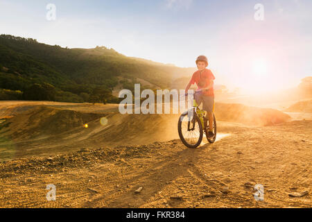 Mixed Race boy riding dirt bike sur la voie Banque D'Images
