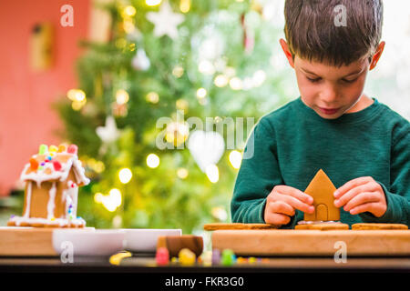 Mixed Race boy building gingerbread house Banque D'Images