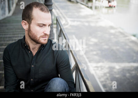 Caucasian man sitting on escalier extérieur Banque D'Images