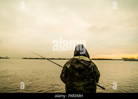 Caucasian man pêche en lac à distance Banque D'Images