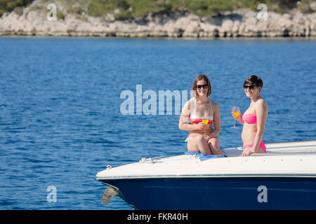 Les femmes de boire des cocktails sur boat in ocean Banque D'Images