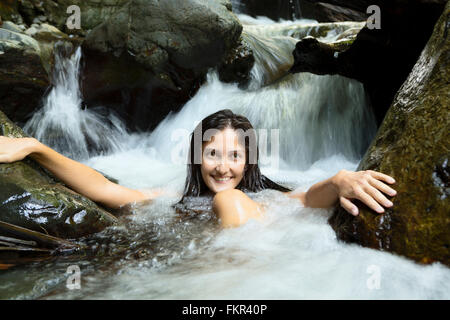 Mixed Race woman sitting in waterfall Banque D'Images