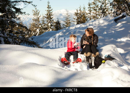 Mère de race blanche et fils de boire un chocolat chaud dans la neige Banque D'Images