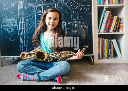 Mixed Race girl holding saxophone sur marbre Banque D'Images