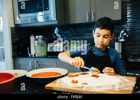 Mixed Race boy pizza dans la cuisine Banque D'Images