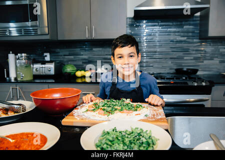 Mixed Race boy cooking in kitchen Banque D'Images