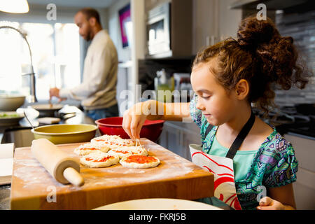 Mixed Race girl cooking in kitchen Banque D'Images