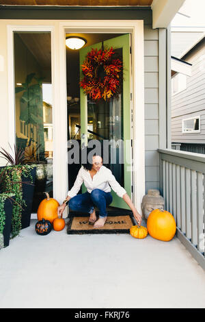 Mixed Race woman organiser pumpkins on patio Banque D'Images