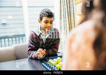 Mixed Race siblings playing board game Banque D'Images