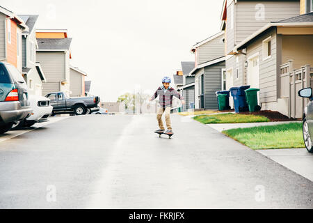 Mixed Race boy riding skateboard sur street Banque D'Images