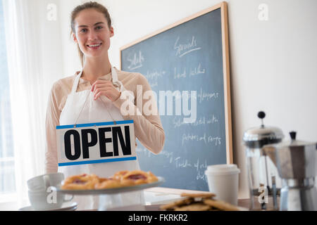 Native American Woman holding open sign in cafe Banque D'Images