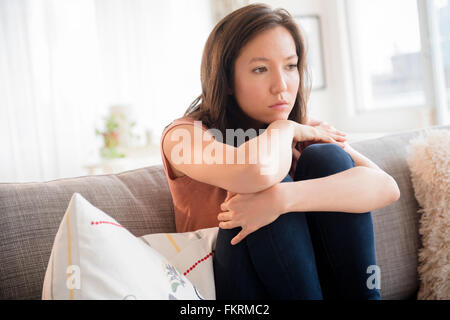 Triste mixed race woman sitting on sofa Banque D'Images