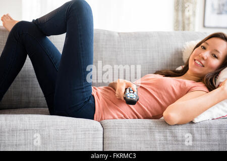 Mixed Race woman watching television Banque D'Images