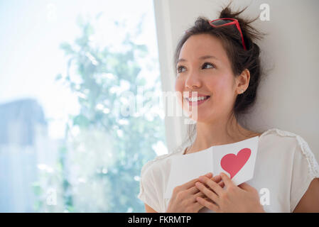 Mixed Race woman holding Valentine card Banque D'Images